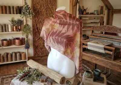 Maniquí con un chal estampado artesanalmente con siluetas de hojas en tonos rojizos y terracota