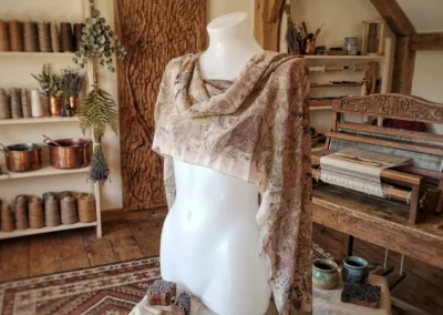 Maniquí vistiendo un chal artesanal estampado con motivos botánicos en tonos marrones y beige