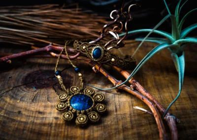 Detalle de pendientes y collares artesanales de macramé con piedras azules entrelazados con ramas