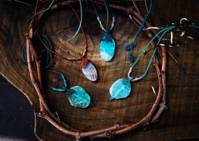 Varios colgantes de macramé con piedras de colores turquesa y azul sobre un fondo de ramas secas