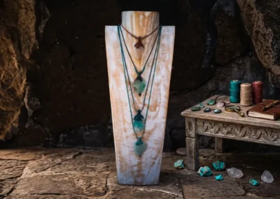 Expositor rústico de madera con varios collares y colgantes artesanales de estilo macramé y piedras naturales